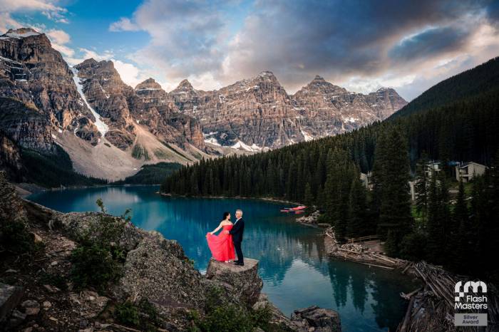 Award Winning photography at Moraine Lake of the couple standing on the rock against Rocky Mountains