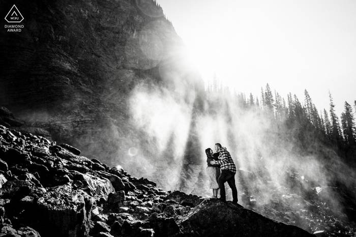 Black and white photograph of engaged couple embraced in a sunlight at Takakkaw Falls