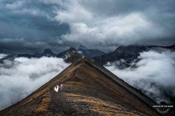 Newlyweds walking on the ridge above the clouds in Banff