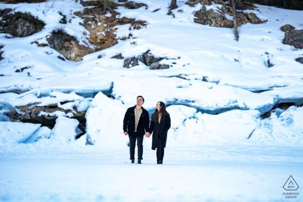 Couple in love walking and holding hands in a winter scenery. On the background an ice-wall.