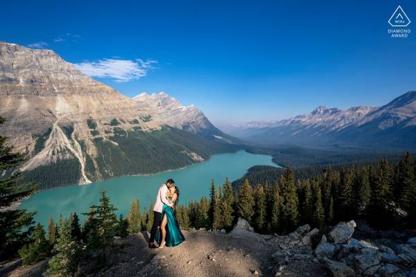 Lady in a long, green dress dances with her fiancee at the studding location Peyto Lake in Canada.