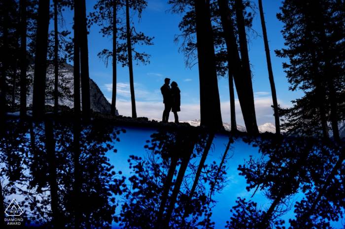 Award wining artistic photograph of the couple in the reflected forest in Banff.