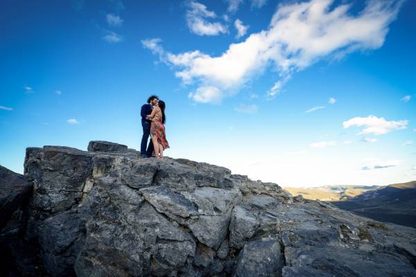 Banff Engagement Photographer created this unique photo of couple in love standing on giant rock in the Canadian Rocky Mountains.