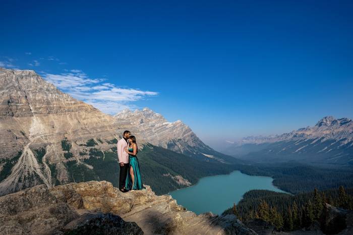 Engaged couple stand at the edge of the mountains at Payto Lake. Amazing moment captured by Banff Wedding Photographer Lukas Slobodzian