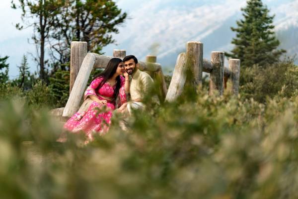 Freshly engaged couple is sitting at the wooden bridge during theit engagement photo shoot in Banff.