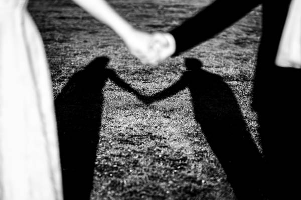 Creative black and white photograph of the shadows of the couple holding their hands.
