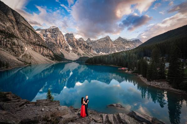 Moraine Lake during stunning sunset. Engaged couple in a hug by the turquoise lake.