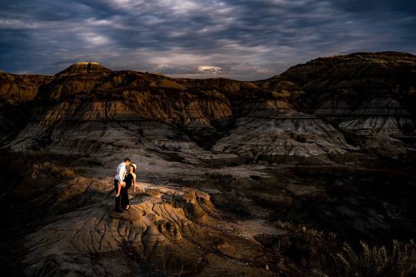 Engaged couple dancing at the stunning location Horseshoe Canyon in Drumheller. They are lighten by the sun. Moment captured by Calgary Wedding Photographer Eliza Slobodzian