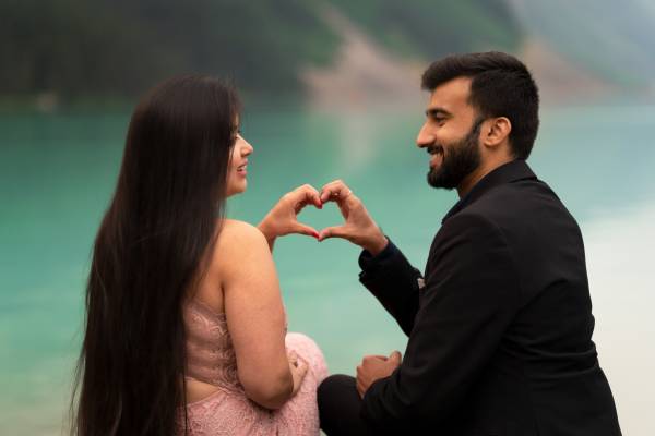Beautiful Indian couple look at each other and creates a hart with their hands.