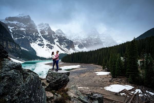 Couple stand on the rock during sunrise engagement session at Moraine Lake