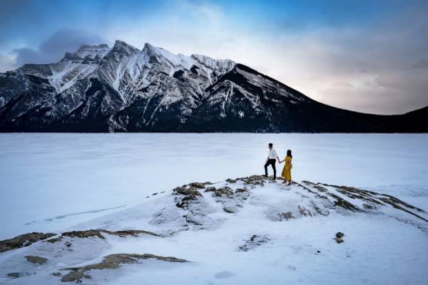 Engaged couple standing at the island at frozen Minnewanka Lake in Banff.