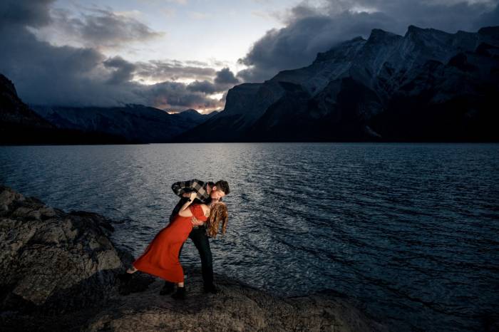 Calgary Wedding Photographer captured a unique moment of engaged couple dancing and kissing during the sunrise in Banff
