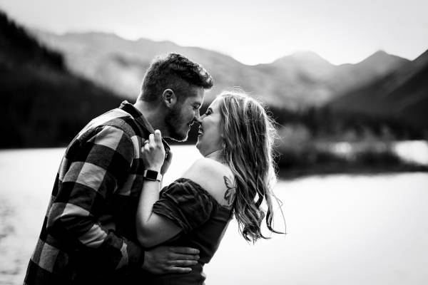 Couple of people in love are having fun and kissing at Minnewanka Lake during their engagement photo session.