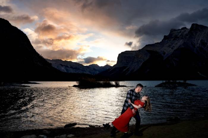 Freshly engaged couple dancing during stunning sunrise at Minnewanka Lake. Engagement moments are captured by Banff Wedding Photographer 4Eyes Photograohy