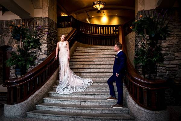 Amazing Wedding Portrait at Fairmont Banff Springs hotel. The bride is walking down the stairs and groom waits for het.