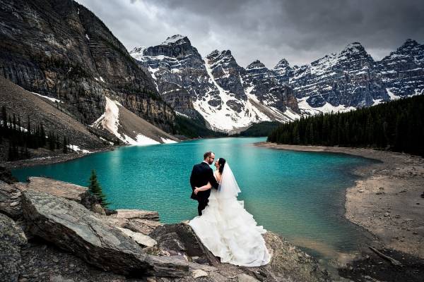 Bride and groom hug each other and adore the view of Moraine Lake in Banff National Park.
