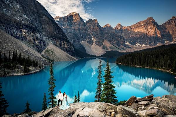 Bride and groom holds and by blue Moraine Lake. Amazing Banff Wedding Photography.