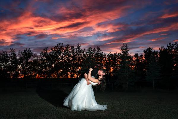 Groom dips the bride while they dance during stunning sunset in Calgary.