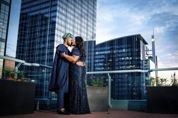 Newlyweds in a traditional blue outfit on the balcony. They share a kiss. On the background the view of the city Calgary.