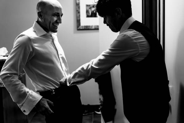 Groomsmen helping the groom to zip his pants before wedding in Bandd