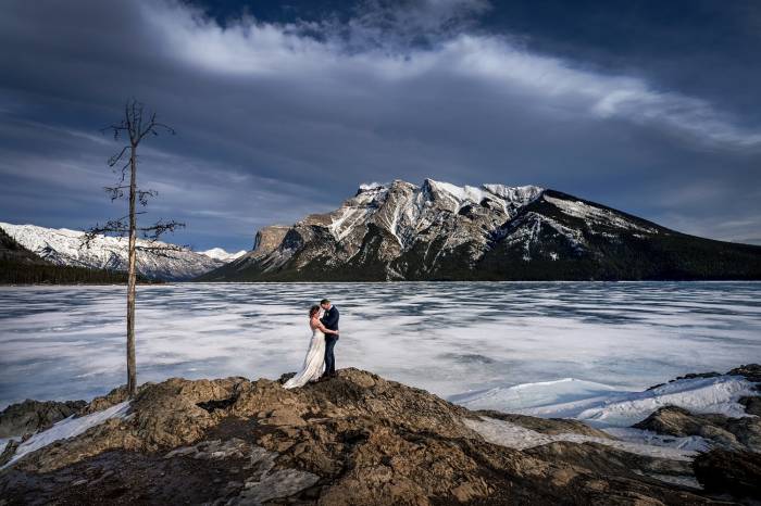 bride and groom hug during windy photo session in Banff.