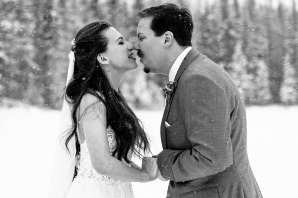 Newlyweds holding their hands and touches their noses during winter wedding in Banff National Park