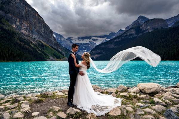 Newlyweds look at each other during photo session at Moraine Lake performed by Banff Wedding Photographers 4Eyes Photography