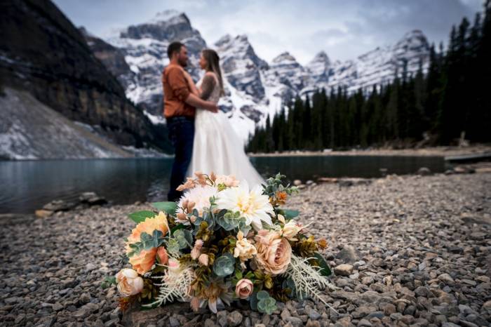 Bride and Groom to be ate hugging each other surrounded by the Canadian Rockies an Moraine Lake.
