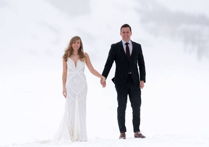 Newlyweds are holding hands during after wedding photo session at Bow Lake