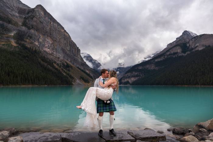 Groom carry the bride on his hands during elopement at Lake Louise