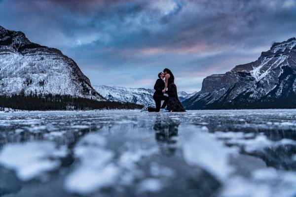 Engagement photo session during stunning sunrise in Banff. A man is proposing on one knee.