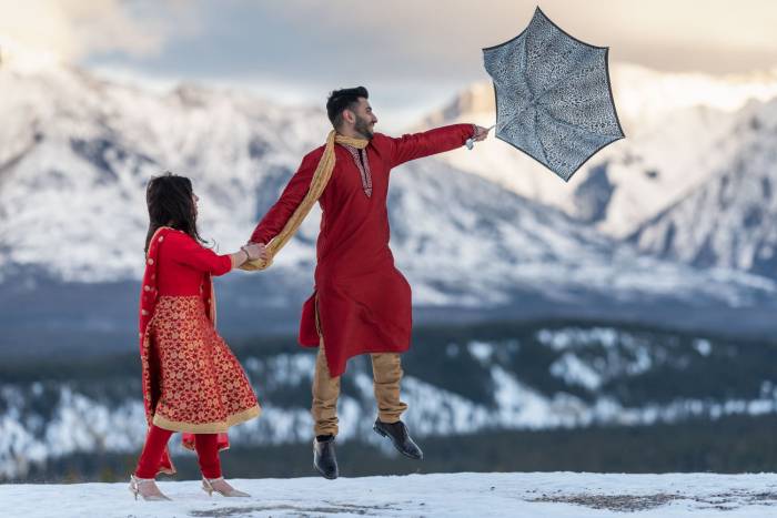 Indian Couple strrugle with strong wind during after wedding session in Banff.