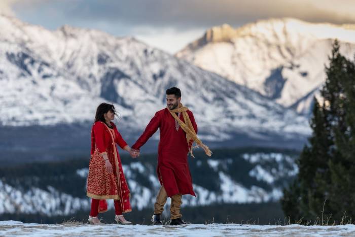 Mountain Indian Wedding. Bride and groom hold hands and walk in the Canadian Rockies.