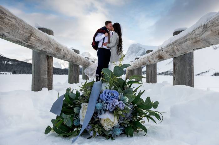 Newlyweds are kissing on the bridge after wedding ceremony in Banff.