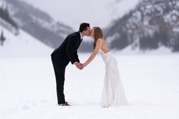 Married couple kissing during winter wedding photo session in Bow Lake.