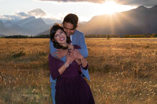 Engagement Photohraphy in Banff National Park. Happy couple is hugging and smiling during goregous sunset.