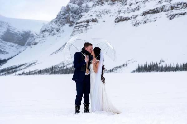 Married couple kissing during winter wedding photo session at Bow Lake.