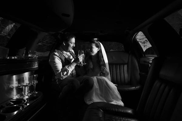 bride and groom drinking champagne in the limo
