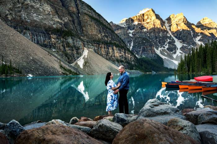 Happily engaged couple looking at each other with love in Banff Moraine Lake