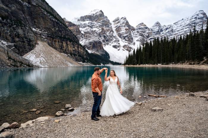 Bride and Groom are dancing at the Moraine Lake in Banff.