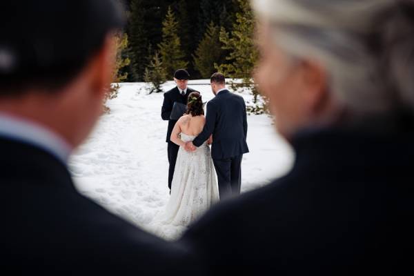 Bride and groom hold their hand during their intimate winter wedding in Banff.