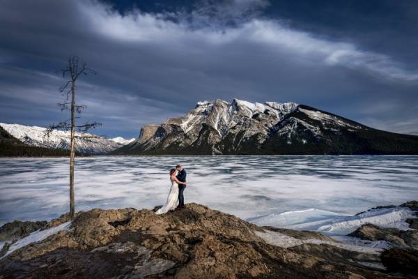 bride and groom hug during windy photo session in Banff.
