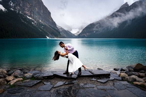 beautiful and young engaged couple dancing at the Lake Louise during their engagement session with best Calgary Wedding Photographer