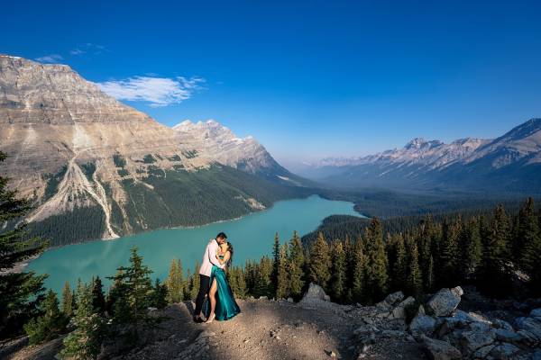 Lady in a long, green dress dances with her fiancee at the studding location Peyto Lake in Canada.