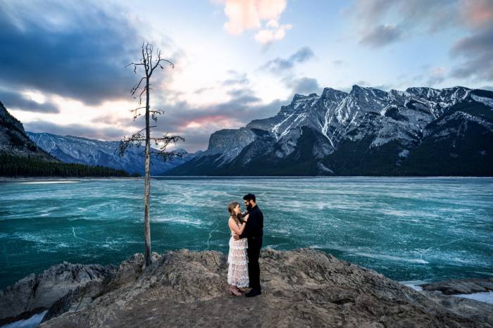 Couple in love facing each other during majestic sunrise at Minnewanka Lake.