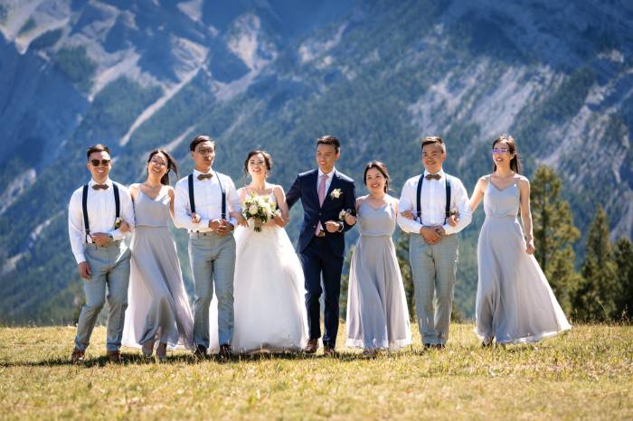 Wedding Party walk with linked arms and have fun at Tunnel Mountain in Banff.