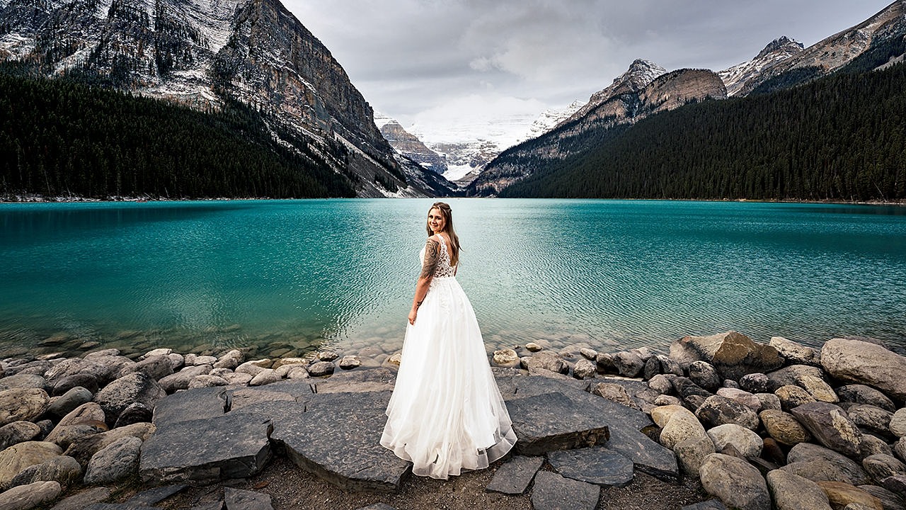 Bride standing by Lake Louise in Banff. | 4Eyes Photography