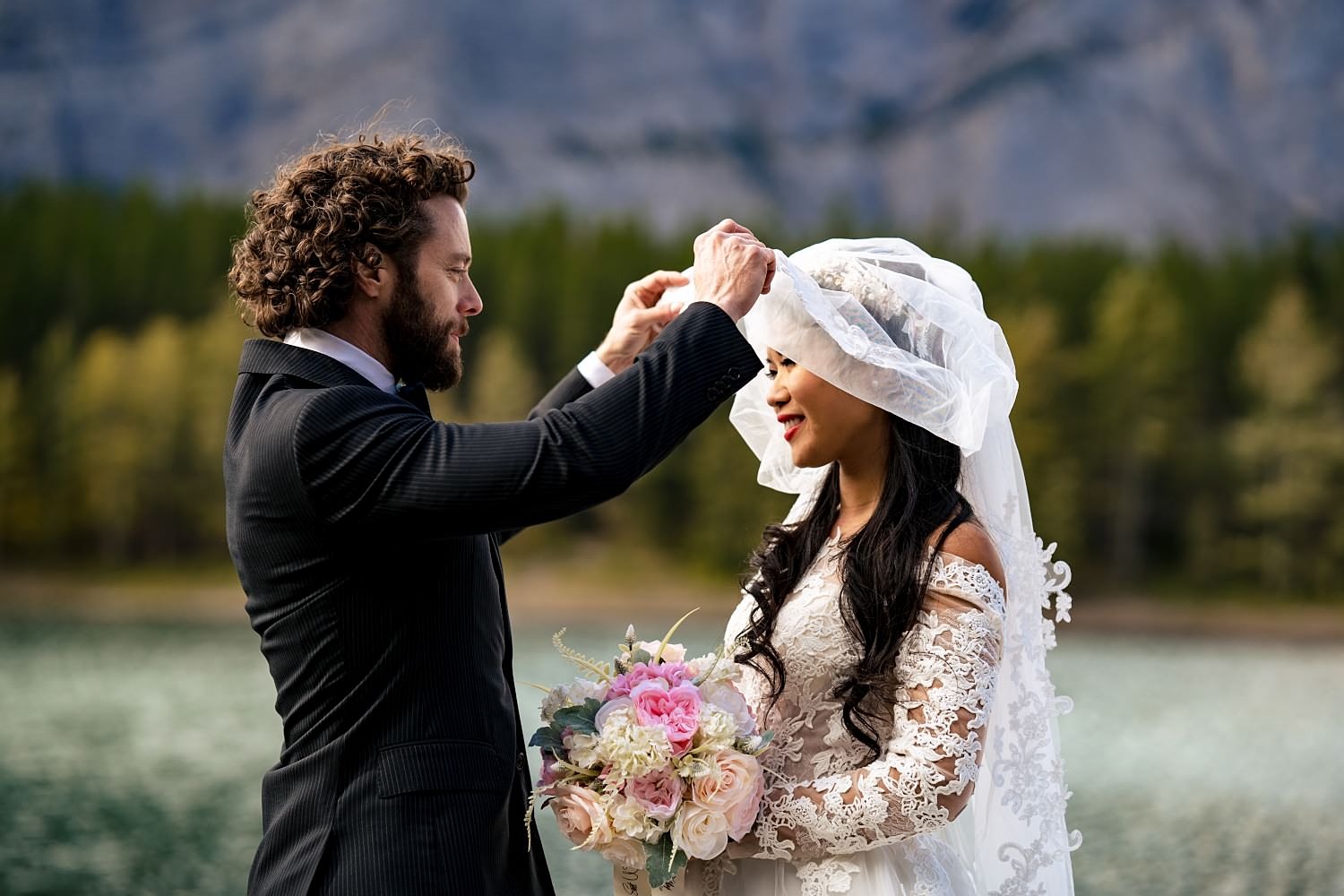 Groom lifts the brides veil during Banff Elopement. | 4Eyes Photography