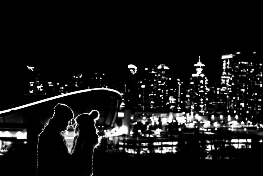 Creative photograph takec by Calgary Wedding photographer of the backlighted couple against a panoramic view of the city Calgary. | 4Eyes Photography