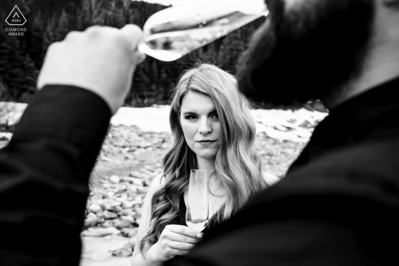 Award Winning Photograph in black and white of the woman through the hand of the man drinking champagne